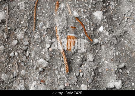 A discarded machine part lies in the gravel, rusty and marked by time - a symbol of transience, technology and industrial decay. Stock Photo