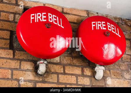 Vintage red fire alarm bells installed in brick wall, fire alarm system, people safety Stock Photo