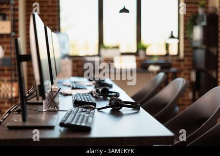 Empty workspace, with no person present, highlighting a modern business setting with desktop monitors. Multiple computers are neatly organized on desks in vacant brick wall office. Stock Photo