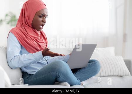 Computer problems. Angry arab woman having issues with laptop at home, annoyed of bad internet connection, free space Stock Photo