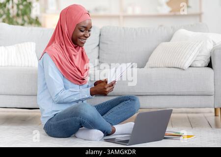 Happy Black Muslim Female Interior Designer Working Remotely With Laptop At Home Stock Photo