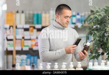 Male buyer scans code on cough syrup to check expiration date Stock Photo