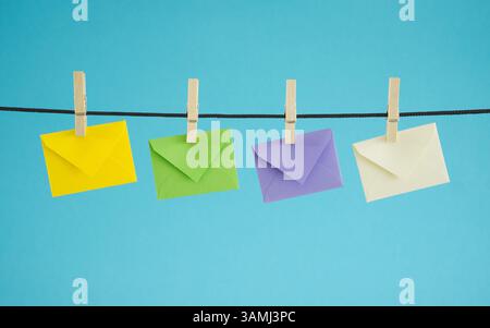 Email marketing campaigns, website newsletter and mailing list concept with four hanged colorful mail envelopes on blue background. Stock Photo
