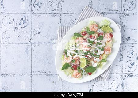 Thai salad with shrimp and rice noodles, pineapple slices, coriander and mint leaves, on a white plate, homemade, no people Stock Photo