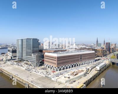 Aerial view of Westfield shopping centre with glass facades surrounded by urban landscape in Hamburg's HafenCity under a clear blue sky, Ueberseequart Stock Photo