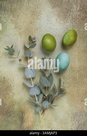 Composition of colored eggs and eucalyptus leaves, on a textured background, Easter card, no people Stock Photo