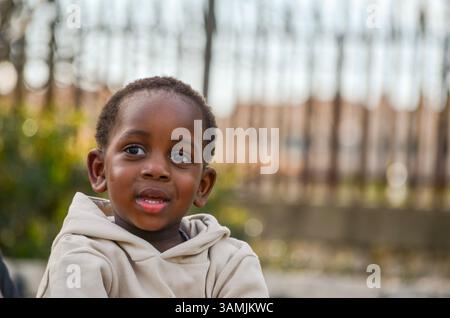 Close-up portrait of a happy african american toddler smiling slightly while looking away from the camera Stock Photo