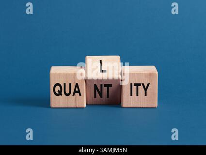 Wooden cubes on blue background with the words quality and quantity symbolize the concept of quality over quantity. Stock Photo