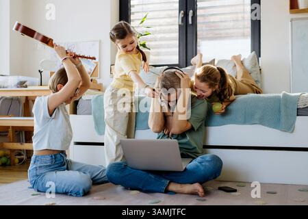 Father with three daughters trying to work from homeoffice. Stock Photo