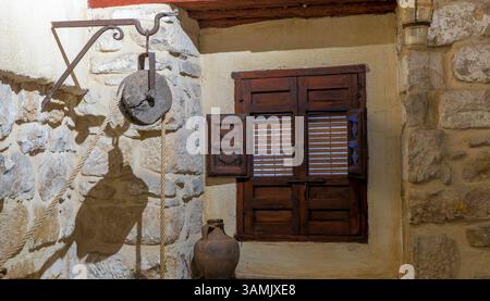 A window with shutters is shown in front of a stone wall. The window is open, and the shutters are closed. The scene has a rustic, old-fashioned feel, Stock Photo