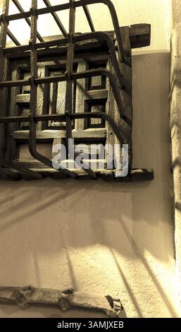 an old window closed with wooden shutters and protected by an iron frame. The photo has a vintage feel to it Stock Photo