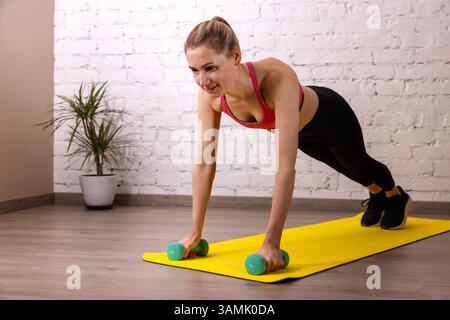 fitness woman doing dumbbell pushups in the gym Stock Photo