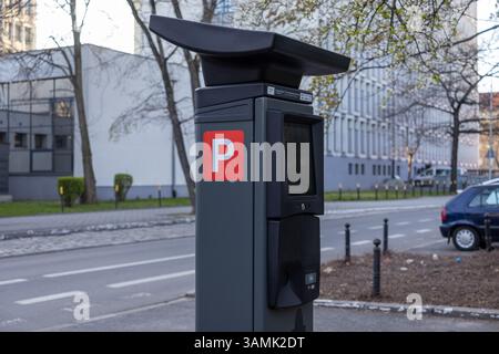 Contemporary parking payment machine with touchscreen and card terminal located on a city sidewalk, featuring a red “P” symbol and surrounded by urban Stock Photo