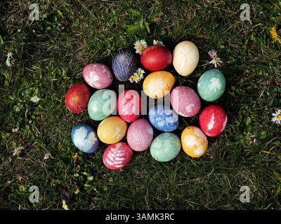 Colorful Easter eggs dyed with store-bought colors. Plants and nets create delicate patterns on the vibrantly colored eggshells. Stock Photo