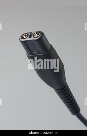 close-up of black electric plug or charging connector of electronic device isolated gray background, with two circular metallic contacts at the top Stock Photo