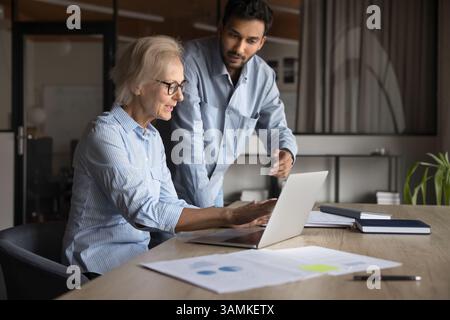 Two diverse colleagues work together using laptop computer Stock Photo