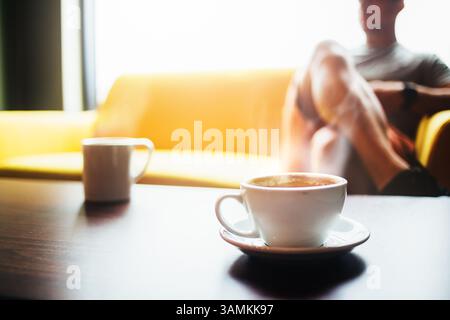 Man sitting on a yellow couch in a coffee shop Stock Photo