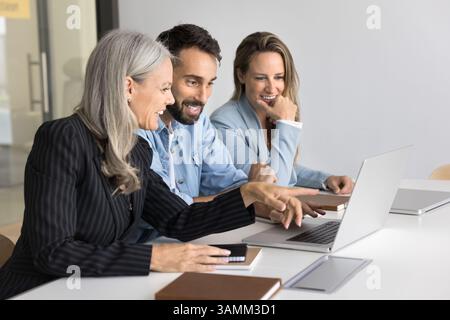 Smiling multicultural group office workers discuss project on notebook screen Stock Photo
