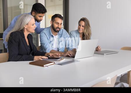 Skilled male mentor explain work on notebook to interns group Stock Photo