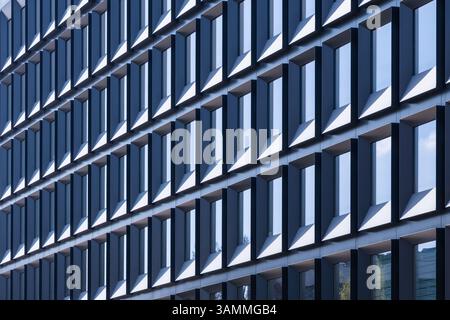 Repetitive modern office building facade with rectangular windows creating abstract geometric pattern, daylight architecture texture background Stock Photo