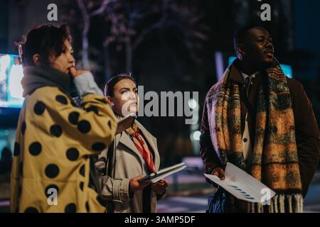 Multiracial people collaborating outdoors during evening while discussing and reviewing documents Stock Photo