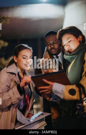 Multiracial group of people collaborating and reviewing documents outdoors in the evening Stock Photo
