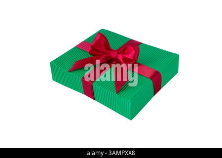 Christmas colors gift box with satin bow isolated on white. Box wrapped with green corrugated paper and tied with red shiny silk ribbon. Coquette styl Stock Photo