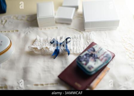 Delicate garter with a blue ribbon rests on a lace tablecloth, surrounded by elegant boxes and a passport, creating a bridal atmosphere. Stock Photo