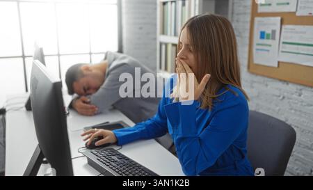 Woman yawning at computer while man sleeps with head down in office showcasing workplace fatigue and diverse employee interactions indoors. Stock Photo