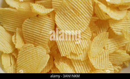 Close-up shot of fresh, crispy potato chips arranged in a pile showcasing texture and golden brown color. Stock Photo
