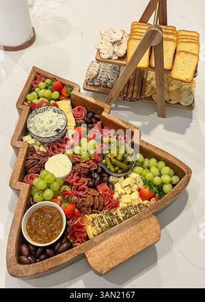 A festive holiday charcuterie spread with meats, cheeses, fruits, dips, and sweet treats served in a tree-shaped tray, perfect for seasonal entertaini Stock Photo
