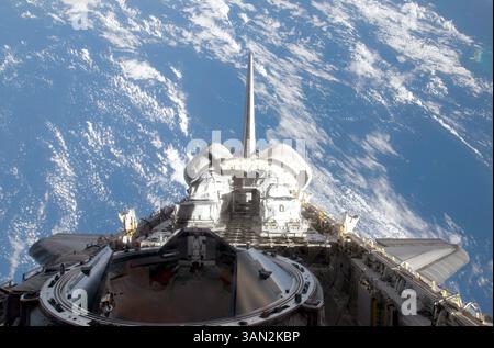 A partial view of Space Shuttle Atlantis backdropped by a blue and ...
