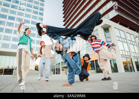 A lively group of friends engaging in an energetic breakdance performance, demonstrating their impressive flow and style while showcasing their unique skills and camaraderie during an exciting dance session Stock Photo