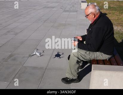Cracow. Krakow. Poland. Old man operating aerial photography drone with remote controller. Stock Photo