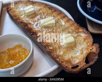 Breakfast composed of toast with butter and marmalade on restaurant table Stock Photo