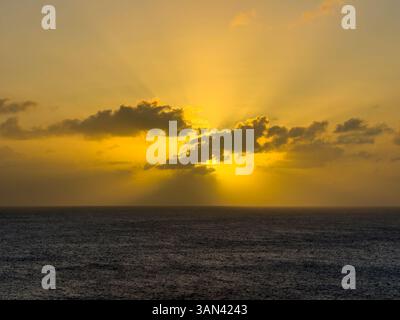 Caribbbean sunset over water with sun rays shining through the clouds Stock Photo