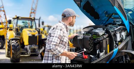 Man using digital tablet to inspect tractor engine with modern modern technology Stock Photo