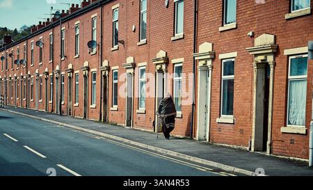 Senior asian woman walking along terrace row in Blackburn,UK Stock Photo