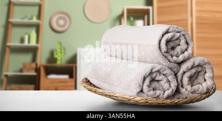 Rolled fresh clean towels on table in bathroom, banner design. Space for text. Home textile Stock Photo