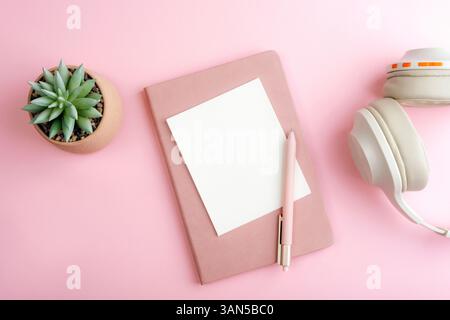 Pink notebook with blank card, pen and succulent plant in pot on pink background. Top view, flat lay, mockup. Stock Photo