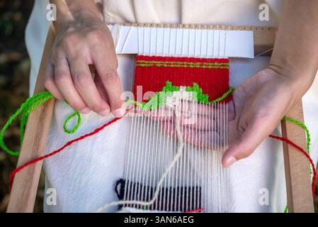Close-up of a woman weaver's hand using a weaving needle on a hand loom. Selective focus. Stock Photo
