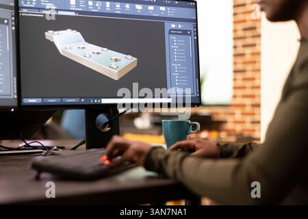 Black female developer designing industrial machinery using creative engineering software. Closeup on african american engineer seated at desk, developing digital clamps and tools on a desktop pc. Stock Photo