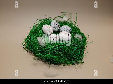 Decorative nest with speckled eggs resting on a green bed of grass-like material for spring celebration Stock Photo