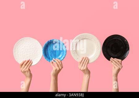 Hands holding empty plates on pink background Stock Photo