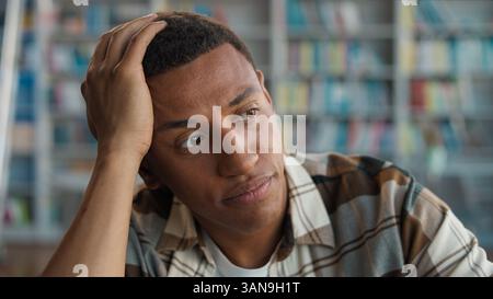 Bored unhappy African American man library student learn study negative educational university dissatisfied male displeased guy boredom tired lazy Stock Photo
