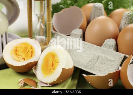 Freshly boiled eggs in half along with a carton of brown eggs Stock Photo