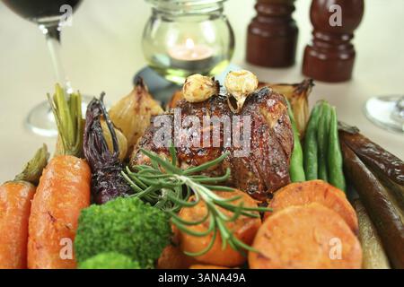 Roast lamb with garlic, broccoli, eggplant, parsnips, onion, carrots, beans, sweet potato, pumpkin and beetroot Stock Photo