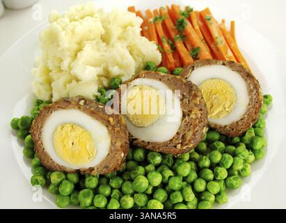 Delicious scotch eggs with peas, carrots and mashed potato Stock Photo