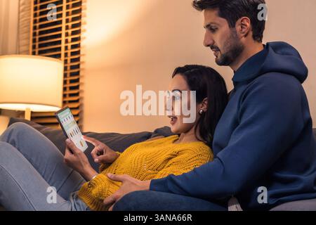 hispanic Couple using digital tablet and browsing online shopping at home during a night promotion Stock Photo