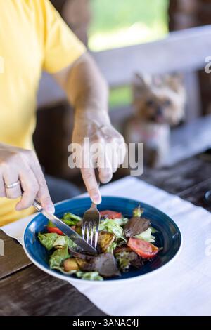 A man is eating a salad with roast beef, tomatoes and fried zucchini on the veranda Stock Photo